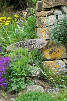 'Garden cottage' wooden sign for a house near stone wall

