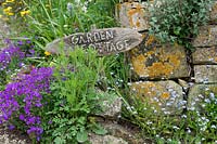 'Garden cottage'  wooden sign for a house near stone wall
