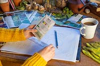 Woman reading back of seed packet at desk.