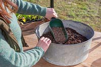 Woman adding horticultural grit into compost to make it free-draining.