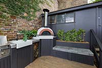 View of outdoor cooking area on terrace patio, with barbecues, sink and pizza oven.
