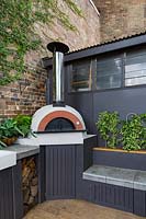 View of outdoor cooking area on terrace patio, with barbecues and pizza oven.
