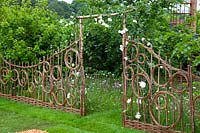 Hazel and willow decorative fence in pattern of circles either side of an arch, in the show garden 'Belmond Enchanted Gardens 