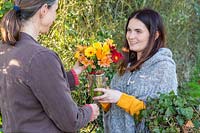 Two women exchanging a gift of a vase of flowers. 