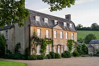 Batcombe House covered with Rosa 'Mme Caroline Testout', Rosa 'Mme Gregoire Staechelin' and Wisteria. 