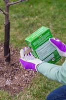 Woman pouring fertiliser into hand from box