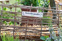 'Im in the garden' sign on a rustic fence
