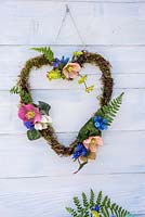 Mossed Heart-shaped wreath decorated with Helleborus, Muscari, ferns and Cyclamen leaves.
