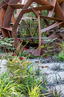 Corten steel sphere by William Roobrouck near ornamental grasses set in paving 
in 'Elements Mystique Garden', Sponsored by Elements Garden Design