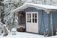 Blue, wooden summerhouse covered by snow in winter.