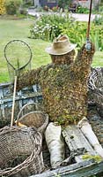 Garden feature of an old rowing boat, fly-fisherman made from moss and 
chicken wire, wicker baskets, net and fishing rod