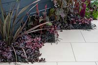 'From Darkness To Light' garden, purple and black colour-themed plant combinations next to white paving
