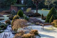 Frosted shrubs and topiary in winter garden. Kilver Court, Somerset, UK.  Designed by Roger Saul of Mulberry.