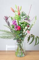 Bouquet of different types of flowers in a glass vase. 

