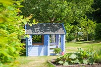 Blue painted children's playhouse in vegetable garden.