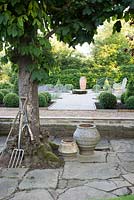 Formal garden with seating, central millstone water feature and topiary