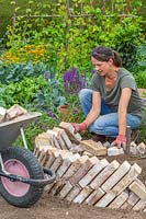 Woman adding second layer of brick to sawtooth raised bed