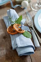 Create your own napkin rings using natural materials - dried orange slices, bay leaves and rosemary tied together with blue gingham ribbon