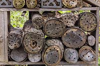 Bug hotel made from cut logs with drilled holes for insects plus straw and twigs