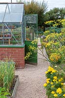 Garden Cottage at Gunwalloe in Cornwall. Cottage garden in autumn. Crittall greenhouse in the vegetable garden.