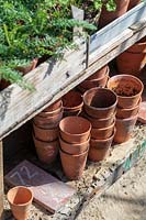 Garden Cottage at Gunwalloe in Cornwall.  Cottage garden in autumn. Neatly stacked terracotta pots showing pot sizes.