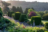 Miserden Park, Gloucestershire, summer, with spectacular views over a deer park and rolling Cotswold hills beyond. Topiary in front of the house.