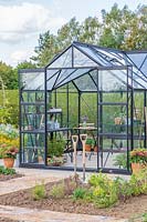 Large greenhouse with double sliding doors in vegetable garden.