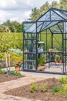 Large greenhouse with double sliding doors in vegetable garden.