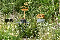 A seating area in a naturalistic wildlife friendly garden with wild and cottage garden flowers, providing a habitat for wildlife, birds, insects and bees. RHS Hampton Court Palace Garden Festival 2019.