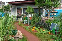 The CANFED Garden: Giving Girls in Africa a Space to Grow. Capturing the spirit of Africa with vivid colours and exotic plants, the rocky red soil is planted with vital edible crops. Behind, a reconstruction of a Zimbabwean classroom. Sponsor: The Campaign for Female Education.