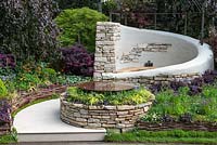 The Kingston Maurward Garden. A romantic curving seating area in Purbeck stone, enclosed in purple beeches, acers and herbaceous planting. Sponsors: Miles Brown, Kingston Maurward College, Goulds Garden Centre, Wilks Landscaping, Holme for Gardens, The Green Gardener.