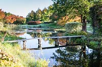 View across the river Orekhovnitza to the narrow wooden bridge to the island. Orekhovno garden, Orekhovno, Pskov Oblast region, Western Russia.