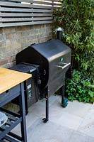 Patio and barbecue in small shade tolerant garden in London with a green theme.