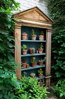 Wooden set of shelves displaying potted plants. 