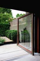 View through open garden sliding door to contemporary garden. 