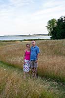 Couple stand on path through meadow, with views beyond to river
 