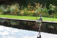 Sculpture of a naked man crouching on a reflecting pool 