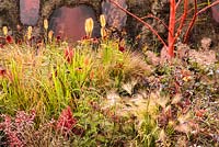 Eruption of Unhealed Anger Garden - planting with Kniphofia 'Tetbury Torch', Achillea 'Walter Funke' and Achillea 'Terracotta' with volcano smoke, lava and ash. RHS Hampton Court Flower Show 2014. Sponsor: RHS and Landform.