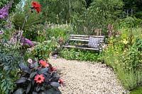 Wooden bench and overgrown flower borders along gravel path -The BBC Spring Watch Garden - RHS Hampton Court Festival - Design: Jo Thompson in consultation with Kate Bradbury