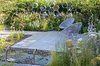 Seating area with two armchairs and rectangular water feature surrounded by aggregate and paving surface  - The Urban Pollinator Garden - RHS Hampton Court Palace Garden Festival, 2019  
Designer: Caitlin McLaughlin