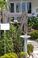 Garden gate made from recycled timber with a freestanding letterbox a sundial with a yacht gnomon in a dry tolerant garden planted with a variety of succulents featuring a Jade Plant.