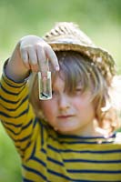 Young boy inspecting a captured insect. 