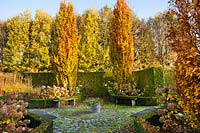Formal garden with circular paving, hedges, relaxing area and pair of Fagus sylvatica 'Dawyck Gold'
