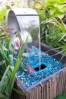 Water feature in a small town garden with tropical foliage plants