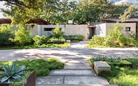 Front garden of a contemporary house with limestone path and architectural planting including Agave in steel raised beds