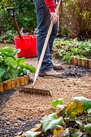 Resurfacing a path by spreading gravel, raking it even and tamping it down