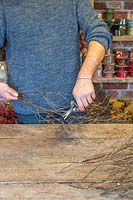 Man using secateurs to cut suitable lengths of birch twigs