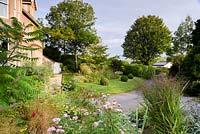 Front garden viewed from mound planted with herbaceous perennials, grasses and shrubs at the Old Vicarage, Weare, Somerset, UK.