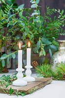 White candles on wooden board as table decoration