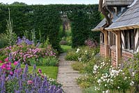 The Shrub Rose Garden. A path leads past the Tea House, a C19 folly, to the herbaceous borders. It is edged in roses, catmint, hardy geraniums and fritillaries. Arley Hall, Cheshire, UK.